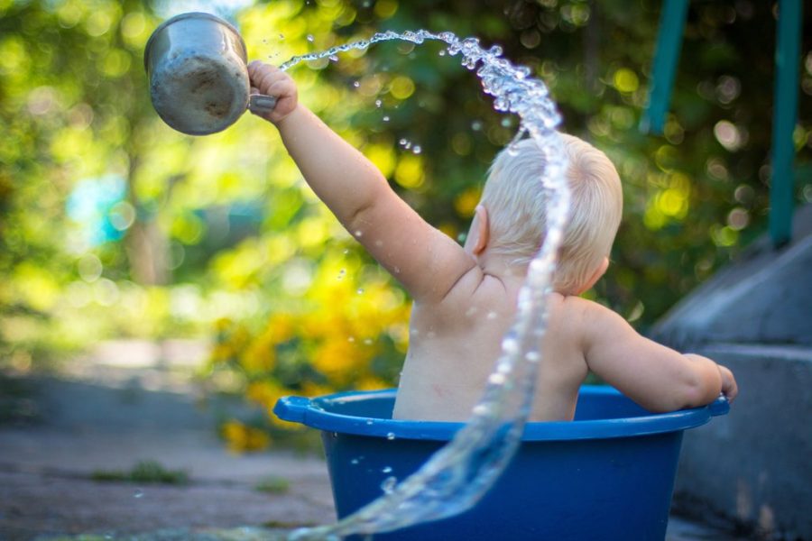 Child taking bath outside in a plastic container