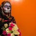 Lady with colorful sugar skull makeup and a bouquet of roses